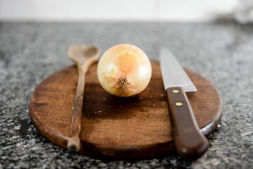 Wall Mural - Closeup of cooking items- a wooden spoon, a knife and an onion on a wooden board