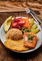 Sticker - Vertical shot of a white plate with salmon, rice, and vegetable salad on a wooden table