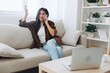 © SHOTPRIME STUDIO - Woman blogger with phone lying at home and talking on the phone on sofa with laptop and working freelancer online, smiling with teeth