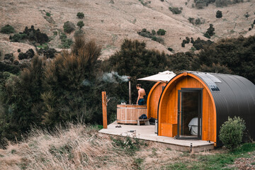 Canvas Print - caucasian guy with bare bust standing inside calm relaxing hot water jacuzzi next to wooden cabin in nice place inside forest among calm nature plants and trees on wooden floor, te wepu pods akaroa