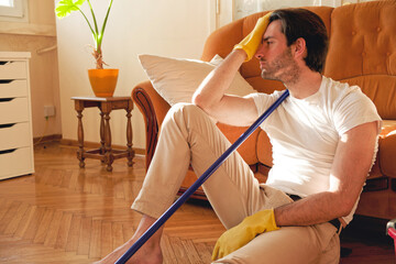 Wall Mural - Handsome man holding vacuum cleaner and feel tired at the home