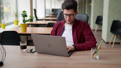 Wall Mural - young freelancer man working with laptop at bright spacious coworking alone. stylish creative design