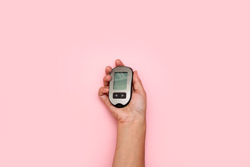 Wall Mural - someone's hand holding an old cell phone on a pink background with copy space in the top left corner