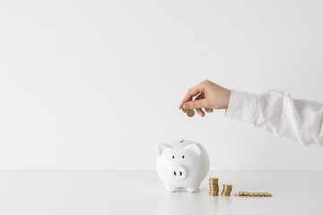 Women counting Australian Dollar coins next to a piggy bank and model house