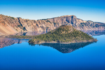 Wall Mural - view of wizard island in crater lake with mirror-like reflections on a calm and clear summer morning