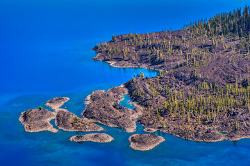 Wall Mural - aerial view of very blue and clear water with a jagged volcanic shoreline.