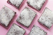 Packaged baked powdered sugar covered chocolate brownies on a pink background