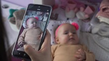 Closeup Of Woman Taking Photo With Smartphone Of Her Cute Baby Daughter On Changing Table, Selective Focus