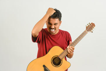 Wall Mural - Portrait of Young Asian man in red t-shirt with an acoustic guitar isolated on white background