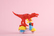 Toy red dinosaur tyrannosaurus rex ride on scooter, pink background. Minimalism creative layout.