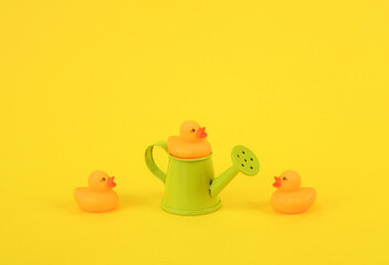 Wall Mural - Rubber little ducklings with watering can on a yellow background