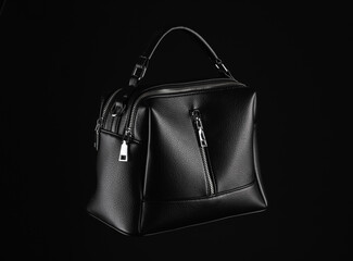 Black leather luxury handbag isolated on black background