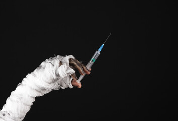 Hands in bandages holding a syringe isolated on black background