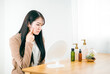 © buritora - 鏡を見ながらニキビ・肌荒れ・湿疹などの肌トラブルに悩む日本人女性（頬）