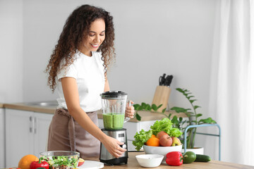 Wall Mural - Young African-American woman making healthy smoothie in kitchen