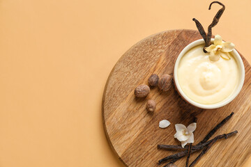 Wall Mural - board with ramekin of tasty pudding, vanilla sticks and nuts on beige background