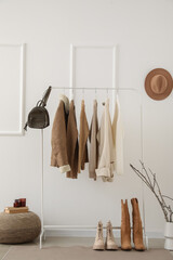 Wall Mural - Rack with warm female clothes, bag and shoes near light wall