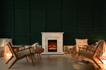 Interior of dark living room with fireplace, burning candles and armchairs