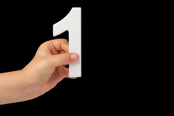 Aufkleber - Number one in a hand isolated on a black background. Number one white in a child's hand on a black background.