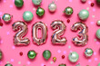 Figure 2023 made of balloons, Christmas balls and confetti on pink background background