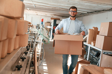 Wall Mural - Moving the boxes with raw material. Print house worker in white clothes is indoors