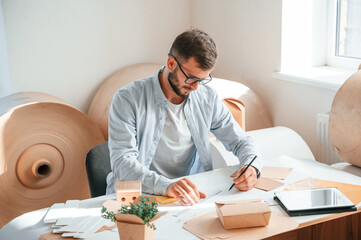 Wall Mural - Drawing by the table. Print house worker in white clothes is indoors