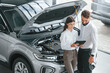 © standret - What's under the hood. Man with woman in white clothes are in the car dealership together
