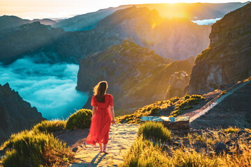beautiful woman in red dress walking barefoot on a very scenic hiking trail in the evening sun on pi