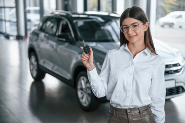 Wall Mural - Young woman in white formal clothes is in the at dealership