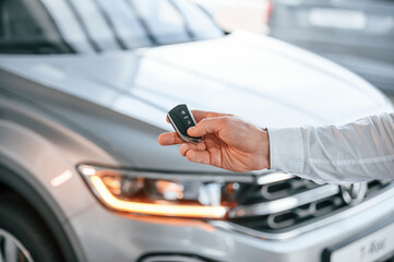 Wall Mural - Keys and remote controller. Close up view. Young man in white clothes is in the car dealership