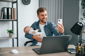 Sticker - Making selfie by smartphone. Father with toddler is indoors in the office