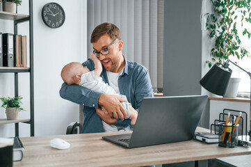 Wall Mural - Having fun. Father with toddler is indoors in the office