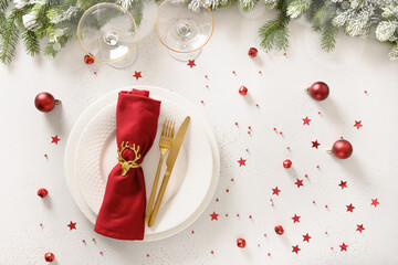 Wall Mural - Christmas table setting with red decorations, wine glasses and champagne on white background. View from above. Copy space. Xmas festive dinner.