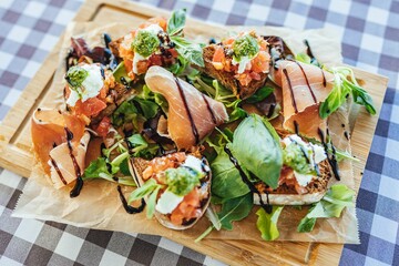 Sticker - Top view of a green salad with jamon and bruschettas on a wooden board on a checkered tablecloth