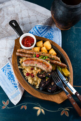 Poster - Sausages, stewed cabbage with cranberries, potatoes, tomatoes and sauce in a cast iron pan.