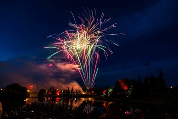 Canvas Print - Glowing fireworks illuminating the night sky with people watching - the concept of holidays