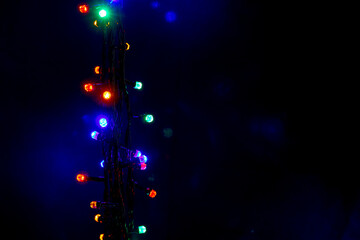 Wall Mural - Christmas and New Year garland with bright multi-colored lights on black isolated background, copy space