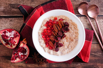 Wall Mural - healthy breakfast oatmeal with pomegranates, cranberries and nuts. top view table scene on a dark wo