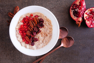 Wall Mural - healthy breakfast oatmeal with pomegranates, cranberries and nuts. top down view table scene on a da