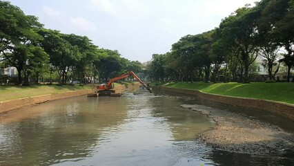 Canvas Print - The excavator digs the sediment in the river to prevent the flood