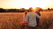 © kieferpix - Parent child relationship. Young father and his two children relaxing in nature meadow watching the beautiful nature sunset.