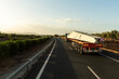 Special transport truck transporting some concrete beams, along a highway at dawn.