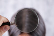 young girl examines her hair with a magnifying glass. hair problem concept