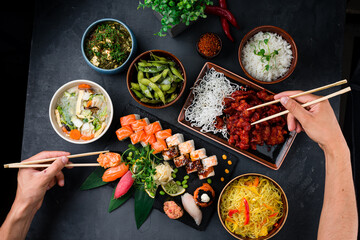 Poster - Set of Chinese dishes on table, hands holding chopsticks sweet and sour chicken, noodles, rice