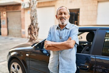Wall Mural - senior grey-haired man smiling confident standing with ars crossed gesture by car at street