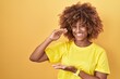 © Krakenimages.com - Young hispanic woman with curly hair standing over yellow background gesturing with hands showing big and large size sign, measure symbol. smiling looking at the camera. measuring concept.