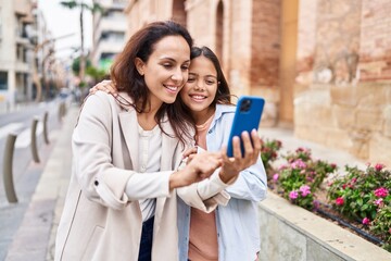 Wall Mural - Woman and girl mother and daughter having video call at street