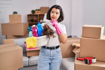 Poster - Young hispanic woman cleaning at new home serious face thinking about question with hand on chin, thoughtful about confusing idea