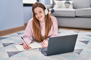 Wall Mural - Young caucasian woman listening to music and studying at home