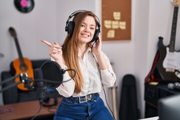 Poster - Young caucasian woman recording song at music studio smiling happy pointing with hand and finger to the side